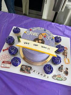 there is a cake that has been decorated with stickers on it and sits on a purple table cloth