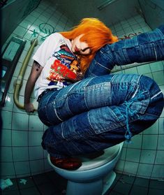 a woman with red hair sitting on top of a toilet