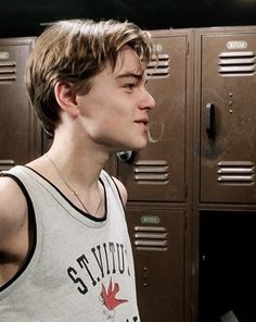 a young man standing in front of lockers with his hand on his hip and looking off to the side