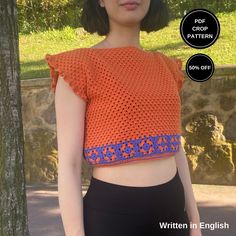 a woman wearing an orange crochet top and black pants with her hands in her pockets