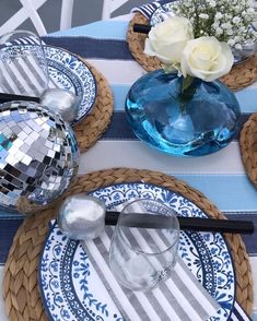 a table set with plates, silverware and flowers on top of it in front of a mirror ball