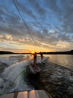 two people riding water skis on top of a body of water under a cloudy sky