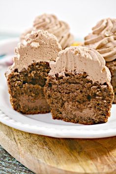 three cupcakes on a plate with frosting and one half cut in half