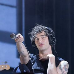 a man with headphones on holding a microphone in his right hand and listening to music