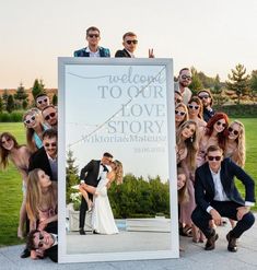 a group of people posing in front of a welcome to our love story photo sign