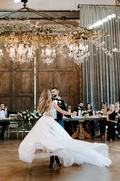 a bride and groom dance together at their wedding reception in an old barn with chandeliers hanging from the ceiling