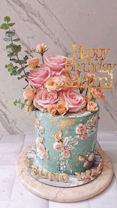 a birthday cake decorated with pink roses and gold letters