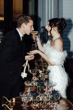 a man and woman standing next to each other at a table filled with wine glasses