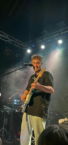 a man standing on top of a stage holding a guitar