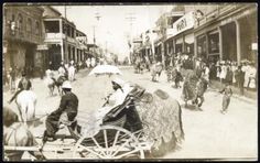 an old black and white photo of people riding in a horse drawn carriage down a city street