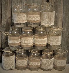 there are many glass jars with lace on the top and bottom, all stacked together