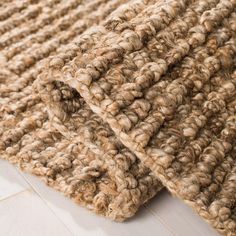 a close up view of a rug on the floor with white wood floors in the background