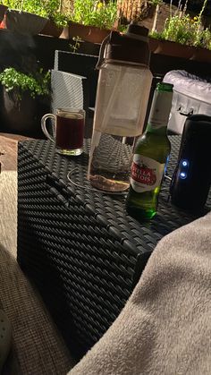 a table that has some bottles on top of it with plants in the back ground