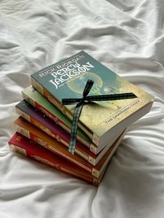 a stack of books sitting on top of a white bed covered in sheets and ribbon