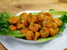 a white plate topped with lettuce covered in chicken wings and garnished with cilantro