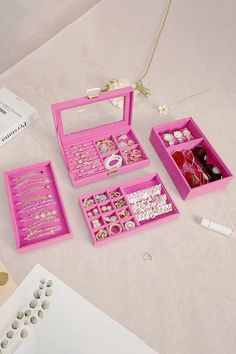 a pink box with jewelry inside sitting on top of a table next to other items