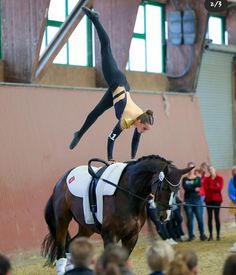 a woman is doing tricks on a horse