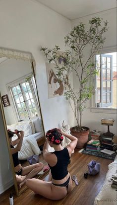 a woman sitting on the floor in front of a mirror