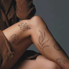 a woman's legs with tattoos on them and flowers tattooed on the leg area