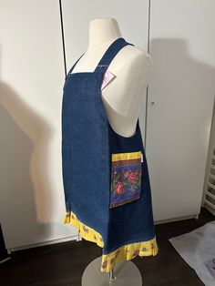 a mannequin wearing a denim apron with patches on it