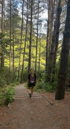 a woman is walking up some steps in the woods on a sunny day with her backpack