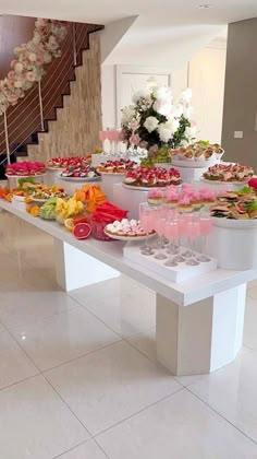 a long table filled with lots of food on top of a white tiled floor next to stairs