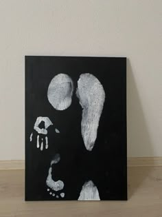 a black and white painting on a wooden floor next to a wall with two feet