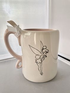 a coffee cup with a tinkerbell on it and a bow around the handle