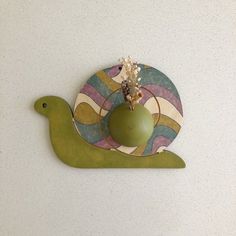 a ceramic bird with a green vase on it's back sitting on top of a wall