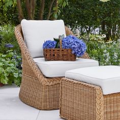 a wicker chair and ottoman with blue hydrangeas in the back yard area