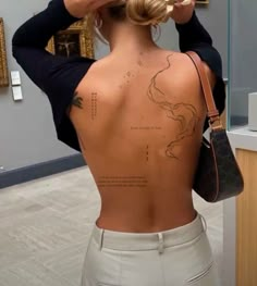 the back of a woman's body with tattoos on it