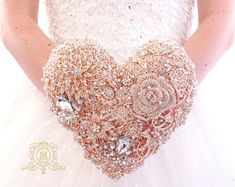 a woman in a wedding dress holding a heart shaped brooch