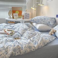 a bed with blue and white bedspread, pillows and a teddy bear on it