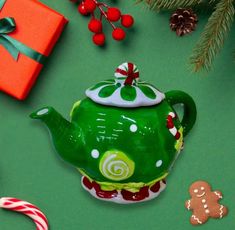 a green teapot sitting on top of a table next to candy canes and christmas decorations