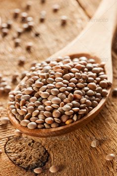 a wooden spoon filled with lots of seeds on top of a wooden table - stock photo - images