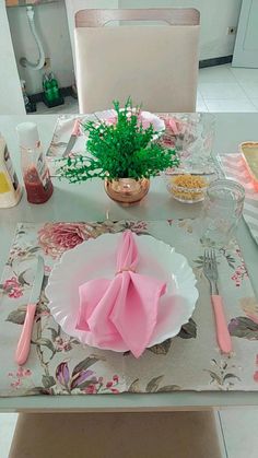 the table is set with pink napkins and place settings for two people to eat