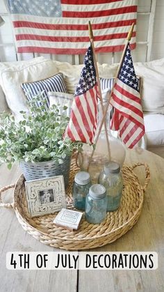 an american flag and two flags on a table in a living room with white couches