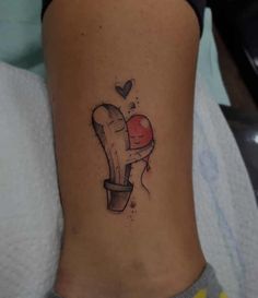 a small cactus tattoo on the side of a woman's leg, with a heart in it