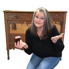 a woman is sitting on the floor with her hand in front of an old dresser