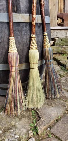 three brooms sitting on top of a wooden barrel