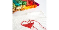 a close up of a piece of cloth with a heart on it next to some thread