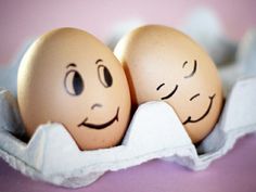 two eggs with faces drawn on them in an egg carton