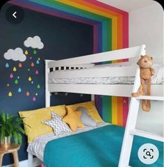 a child's bedroom with rainbow painted on the wall and white bunk bed frame