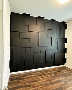 an empty room with wood flooring and black wall paper on the walls, in front of a doorway