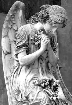 black and white photograph of an angel with flowers in her hands by corbi