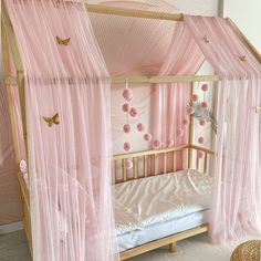 a pink canopy bed with sheer curtains on the top and bottom, in a girls'bedroom