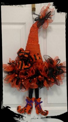 an orange and black dress hanging on the front door with matching shoes for halloween decoration