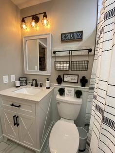 a white toilet sitting next to a sink in a bathroom under a mirror and lights