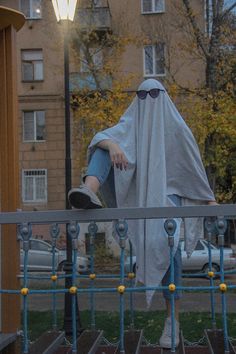 a person sitting on top of a metal fence next to a street light and building