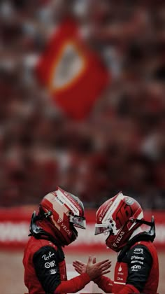 two football players sitting on the sidelines with their hands together